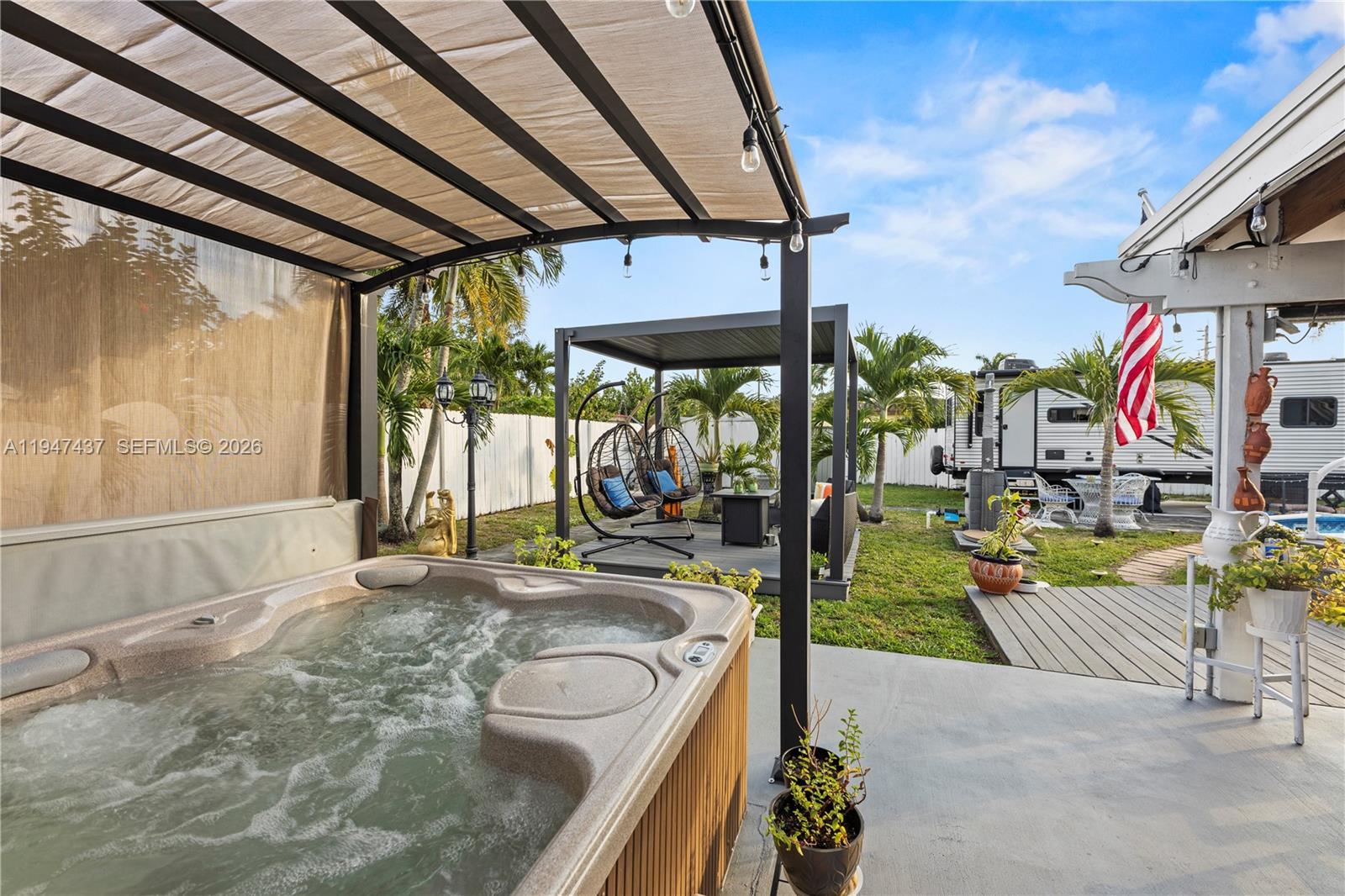 A backyard patio features a hot tub, a covered seating area, and a parked camper — 117 SW 6th St, Hallandale Beach FL 33009, HALLANDALE BEACH, FL