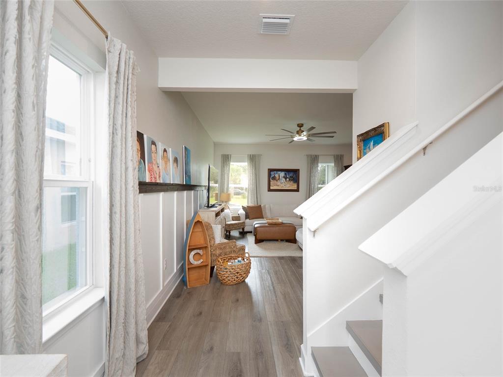 A view from a staircase looking into a living room with wood-look flooring — 11026 HIGH NOON TRAIL, PARRISH, FL