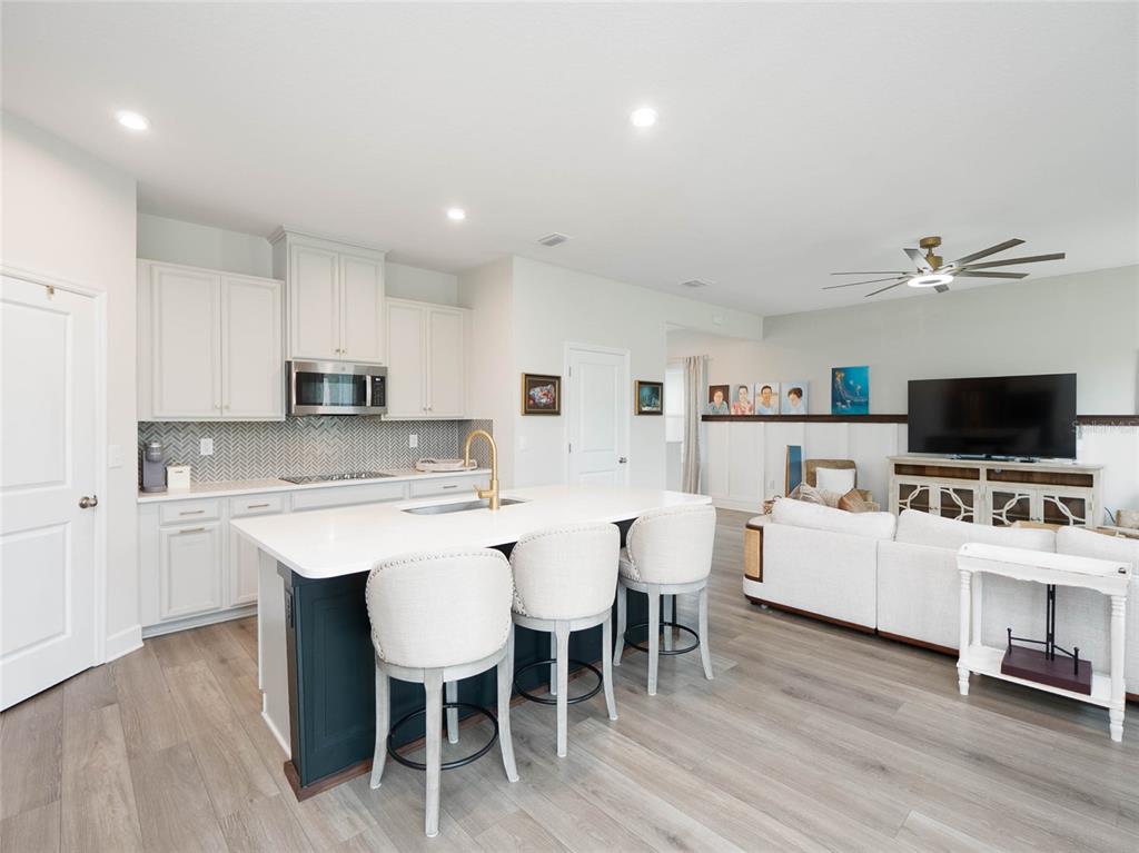 A kitchen with a dark island and white cabinets opens into a living area — 11026 HIGH NOON TRAIL, PARRISH, FL