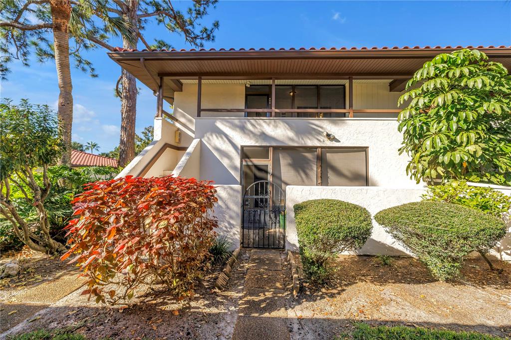 The exterior of a two-story residential building features a screened entrance and a balcony — 3500 EL CONQUISTADOR PARKWAY UNIT 108, BRADENTON, FL