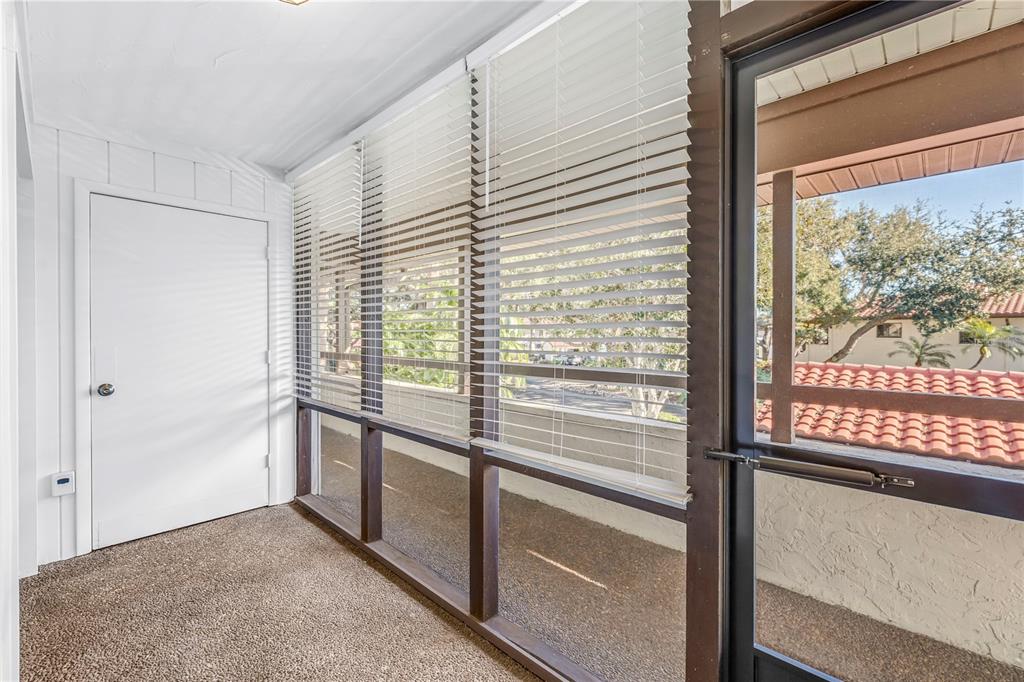 A sunroom with carpeted flooring, white walls, and large windows covered by horizontal blinds — 3500 EL CONQUISTADOR PARKWAY UNIT 108, BRADENTON, FL
