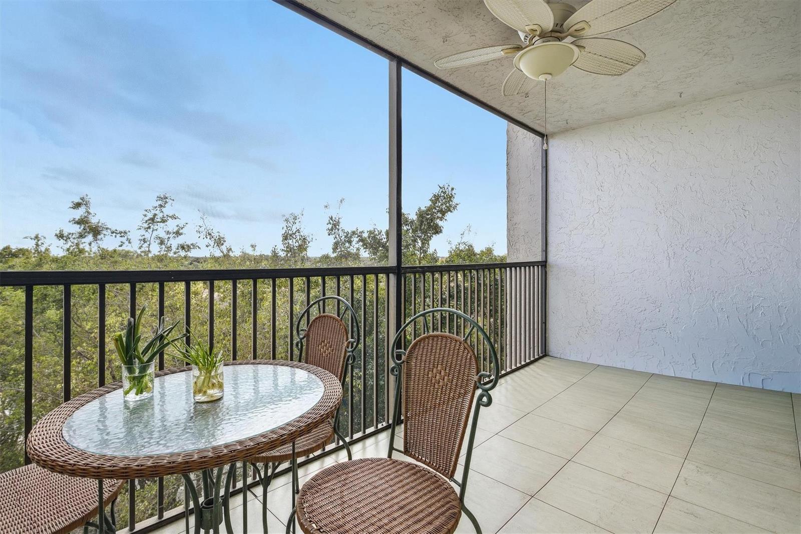 A screened-in balcony features a glass-top wicker table, two chairs, and a ceiling fan — 3910 Inverrary Boulevard # B, Lauderhill FL 33319, LAUDERHILL, FL