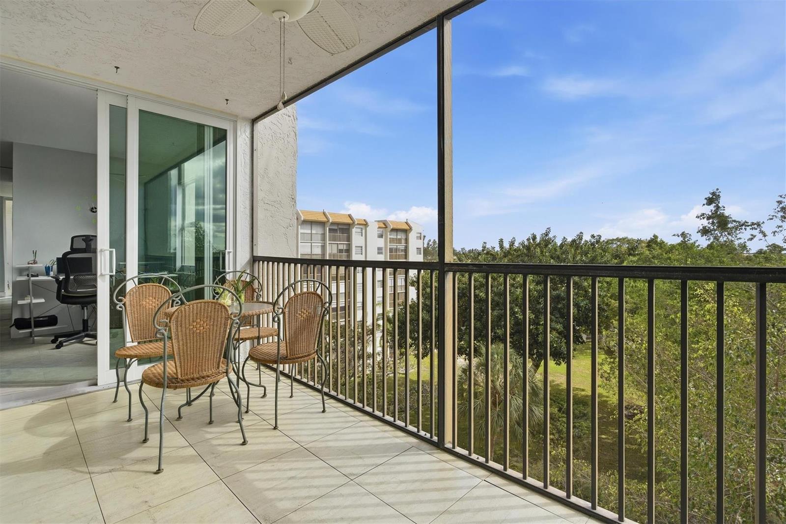A screened-in balcony with tile flooring, patio furniture, and a view of nearby buildings — 3910 Inverrary Boulevard # B, Lauderhill FL 33319, LAUDERHILL, FL