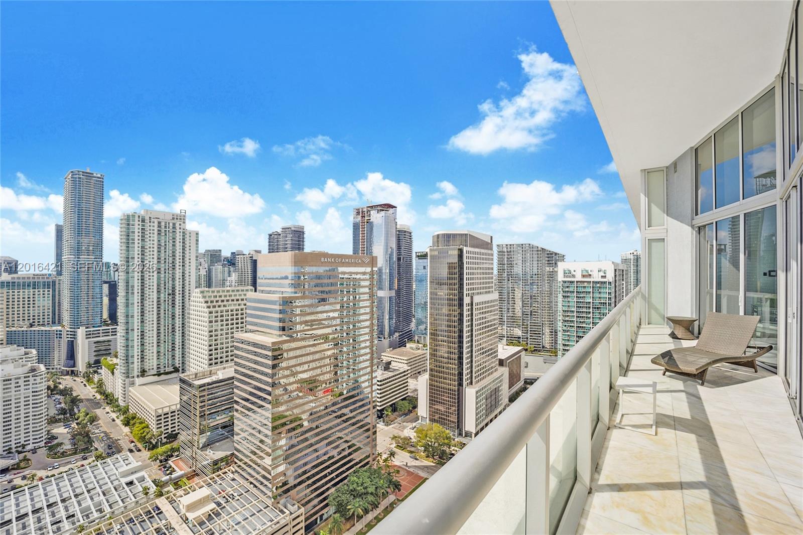 A high-rise balcony with marble flooring overlooks a dense city skyline under a blue sky — 495 BRICKELL AVE # 4101, Miami FL 33131, MIAMI, FL