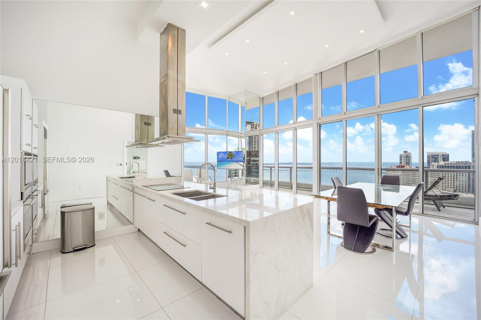 A modern white kitchen with a marble island and floor-to-ceiling windows overlooking the ocean — 495 BRICKELL AVE # 4101, Miami FL 33131, MIAMI, FL