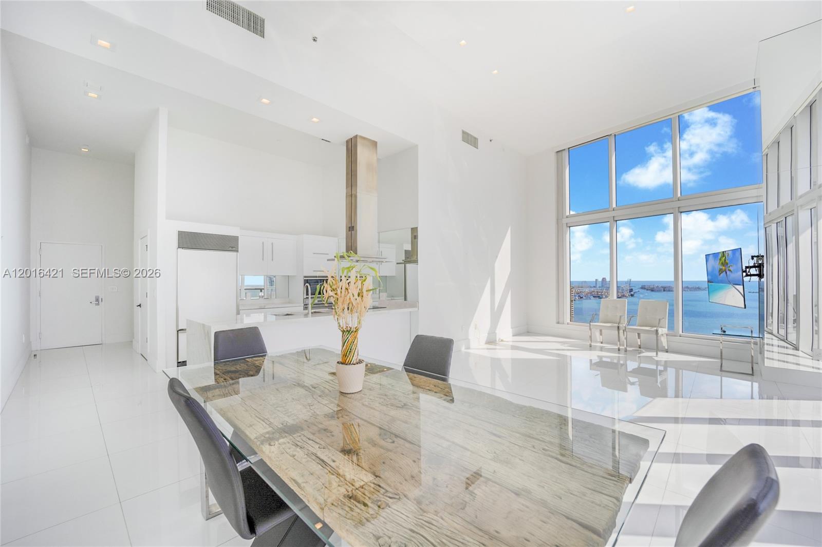 A bright, modern dining area features a glass-topped table, white tile floors, and floor-to-ceiling windows — 495 BRICKELL AVE # 4101, Miami FL 33131, MIAMI, FL