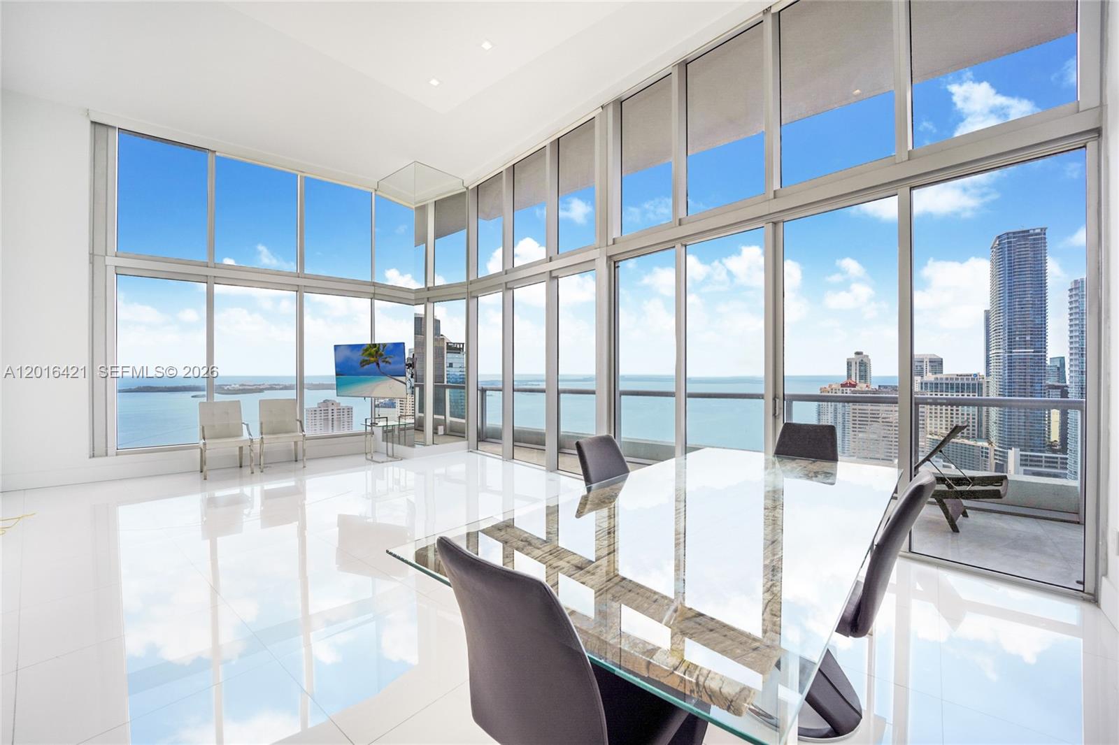 A modern dining room features floor-to-ceiling windows with expansive ocean and city skyline views — 495 BRICKELL AVE # 4101, Miami FL 33131, MIAMI, FL