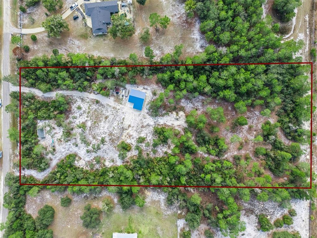 An aerial view shows a rectangular lot with a blue-roofed building and wooded areas — 324 SUMMERVILLE LANE, SANFORD, FL