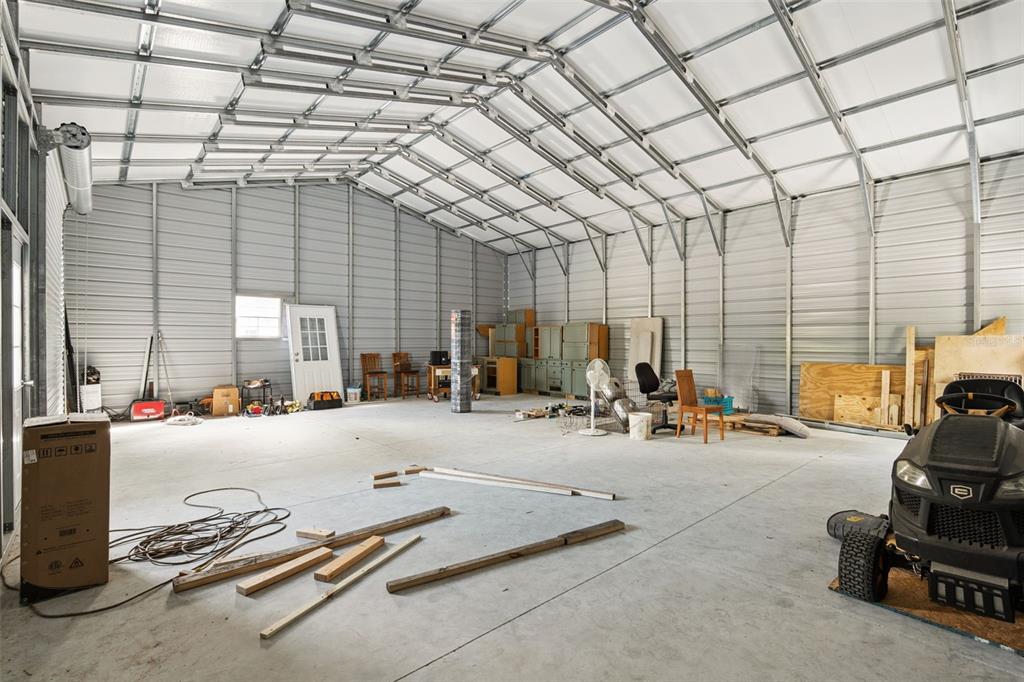 A large, unfinished metal workshop with a concrete floor and exposed steel framing — 324 SUMMERVILLE LANE, SANFORD, FL