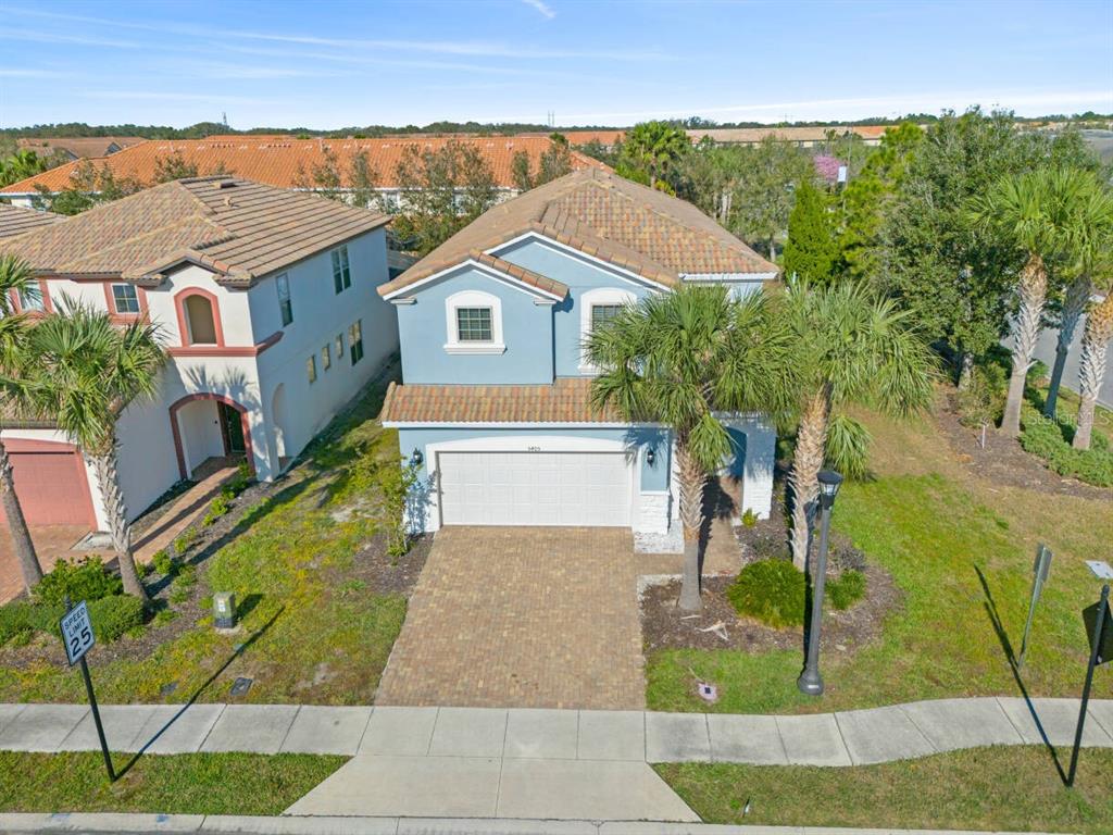 An aerial view of a two-story blue house with a paved driveway and palm trees — 5405 MISTY OAK CIRCLE, DAVENPORT, FL