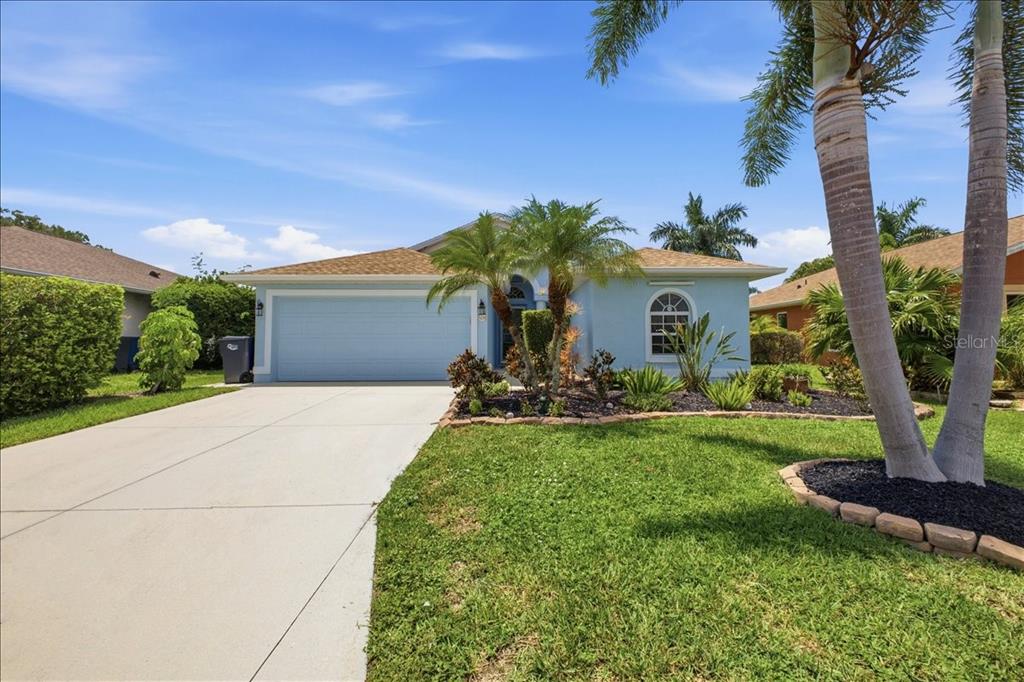 A light blue single-story house features a two-car garage, palm trees, and a concrete driveway — 5231 LANSDOWNE WAY, PALMETTO, FL