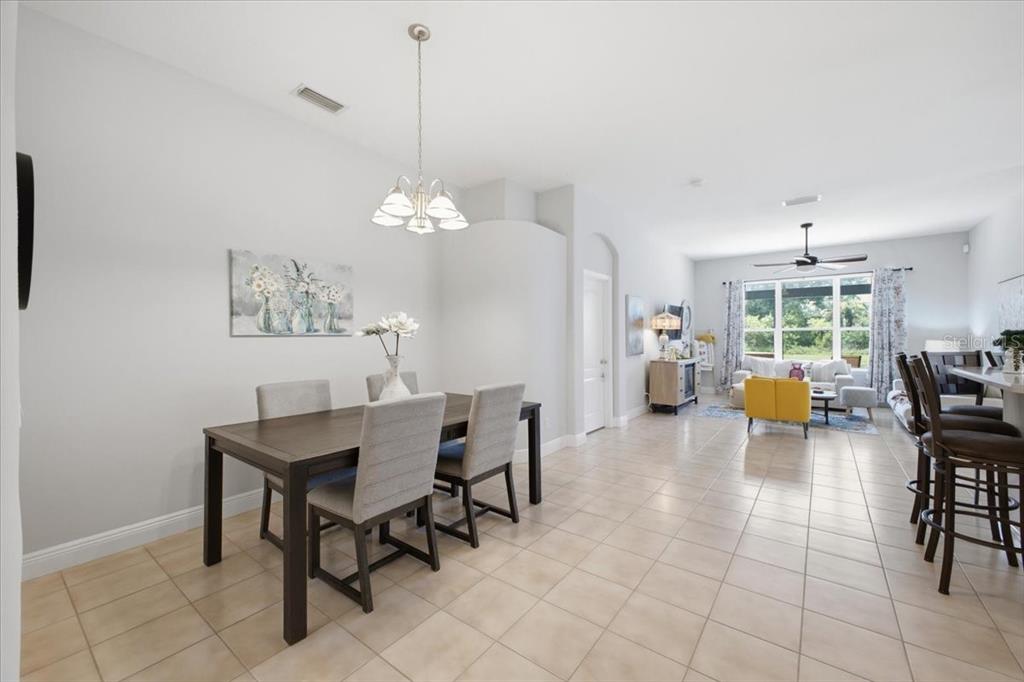 An open-concept dining and living area features tile flooring, neutral walls, and a chandelier — 5231 LANSDOWNE WAY, PALMETTO, FL