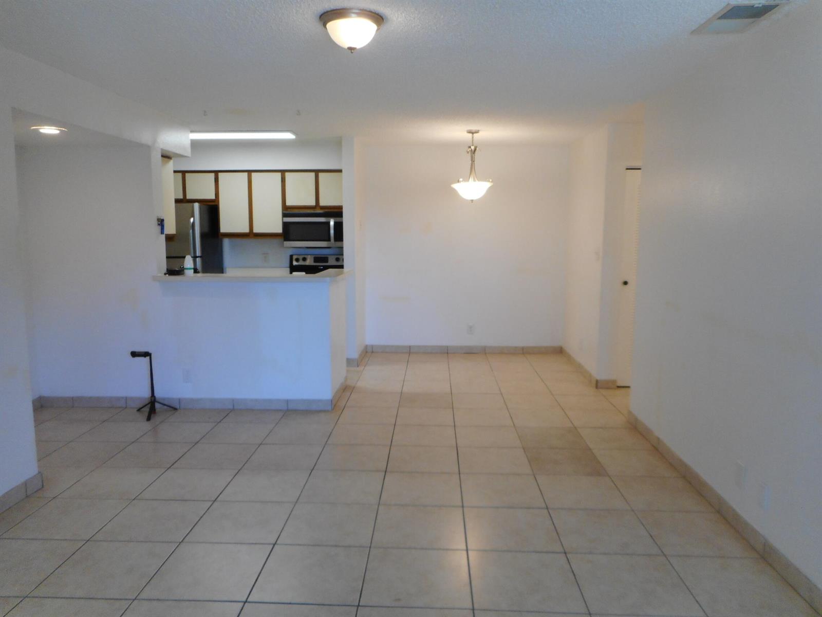 An open-concept dining area with tile flooring connects to a kitchen with white cabinetry — 2900 S University Drive # 9210, Davie FL 33328, DAVIE, FL