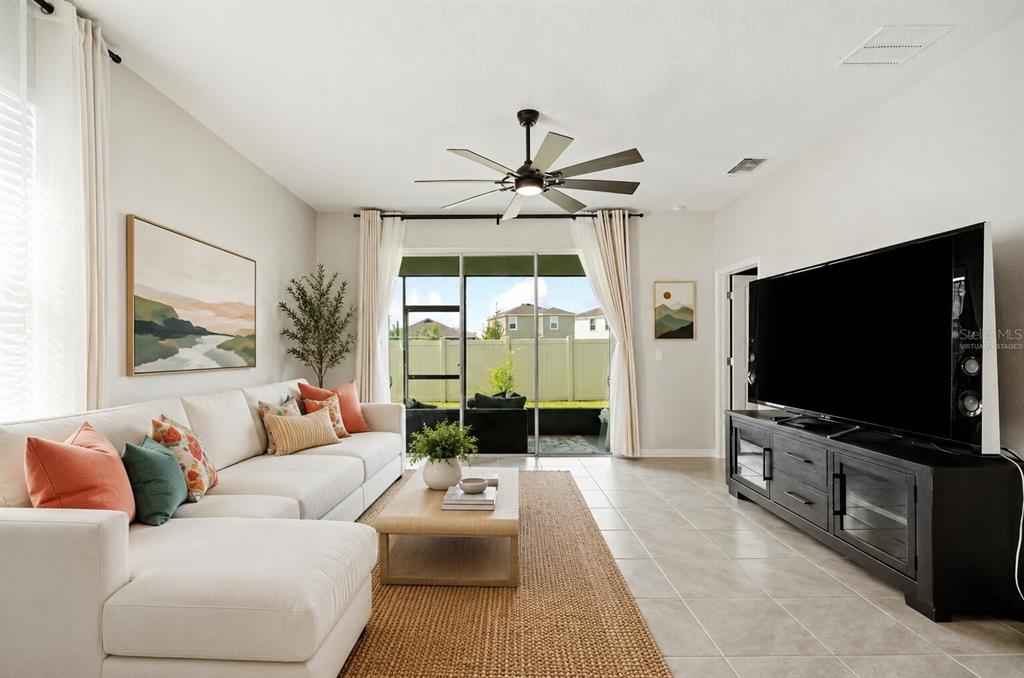 A living room features a white sectional sofa, a television console, and sliding glass doors — 31398 ANCIENT SAGE ROAD, WESLEY CHAPEL, FL