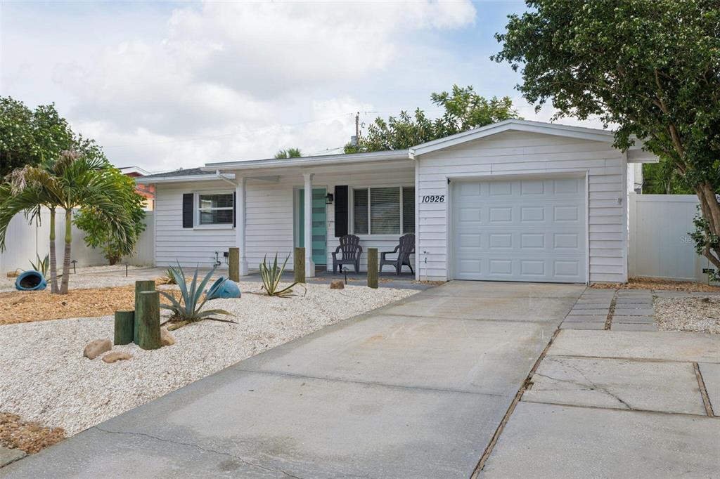 A white single-story house features a front porch, a garage, and a gravel yard — 10926 TEMPLE AVENUE, SEMINOLE, FL