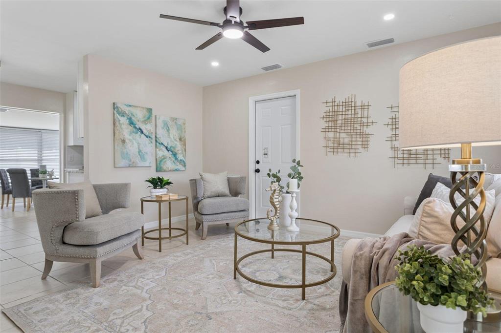 A living room features two gray armchairs, a glass coffee table, and a ceiling fan — 10926 TEMPLE AVENUE, SEMINOLE, FL