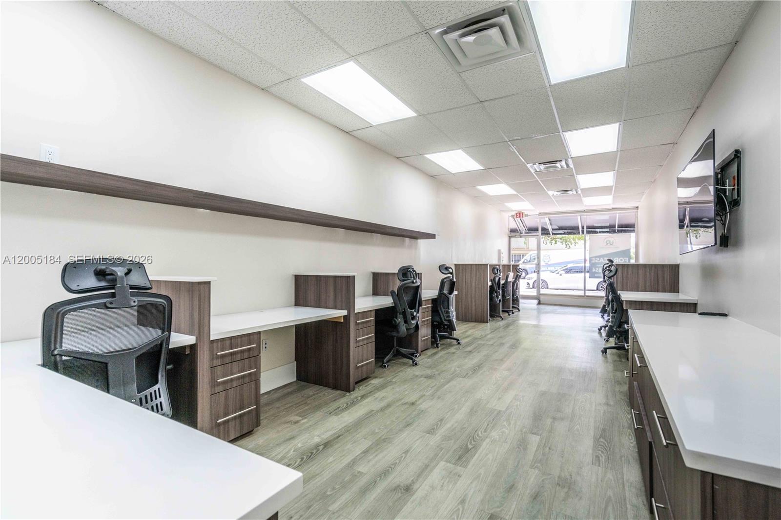 An office space features multiple workstations with white desks, dark wood cabinets, and rolling chairs — 1197 71 St, Miami Beach FL 33141, MIAMI BEACH, FL