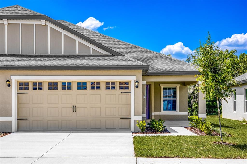 A tan house exterior features a two-car garage, a covered entryway, and a gray roof — 3171 SEVILLE STREET, LAKE ALFRED, FL