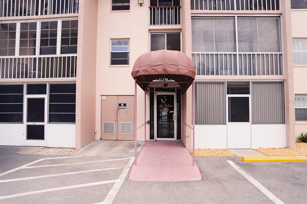 The exterior of a multi-story apartment building features a covered entrance with a brown awning — 519 ALBEE FARM ROAD UNIT 110, VENICE, FL