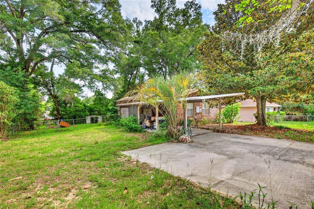 A concrete driveway leads to a small house with a carport and a grassy yard — 3660 SE 139TH LANE, SUMMERFIELD, FL