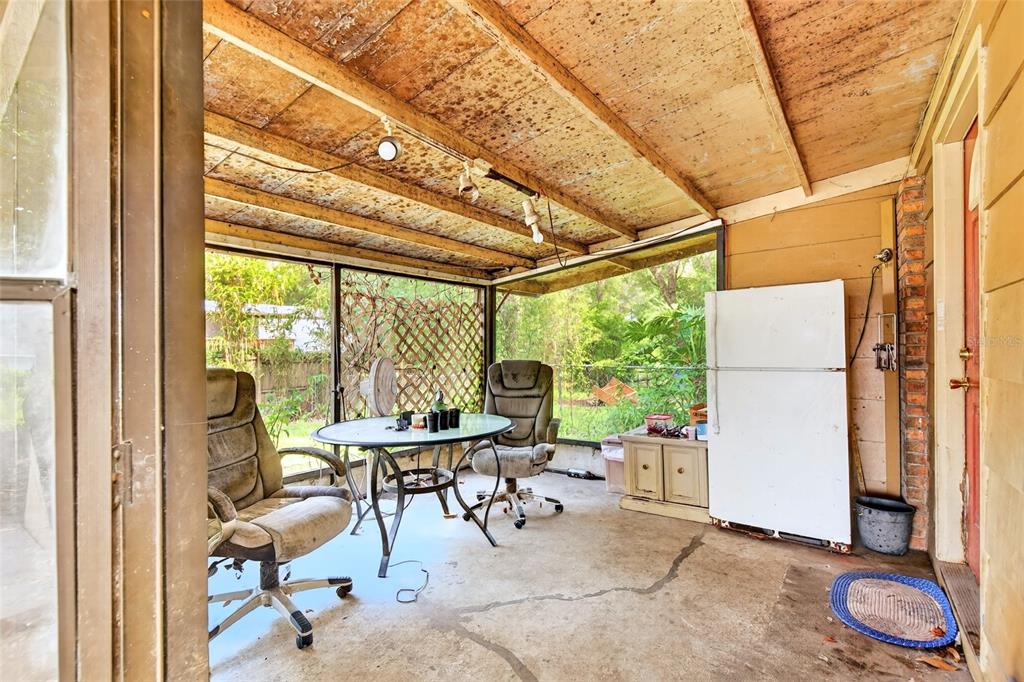 A covered outdoor patio features a concrete floor, a table with chairs, and a refrigerator — 3660 SE 139TH LANE, SUMMERFIELD, FL