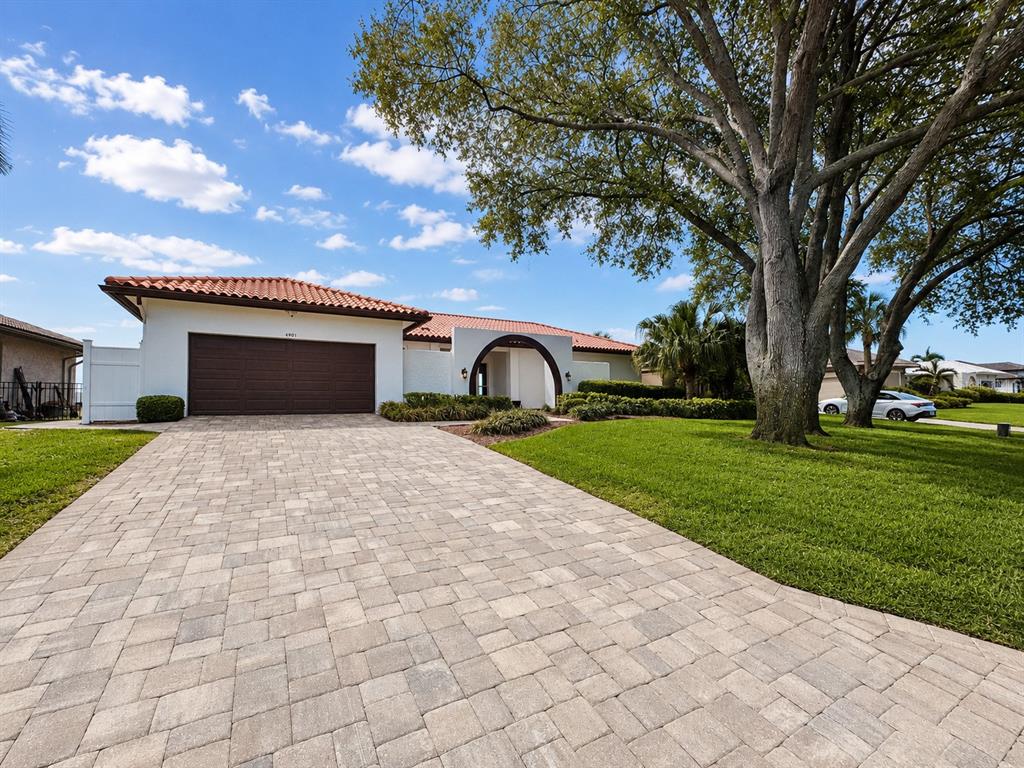 A single-story house with a tiled roof, arched entryway, and a paved driveway — 4901 LANSING ST NE, ST PETERSBURG, FL