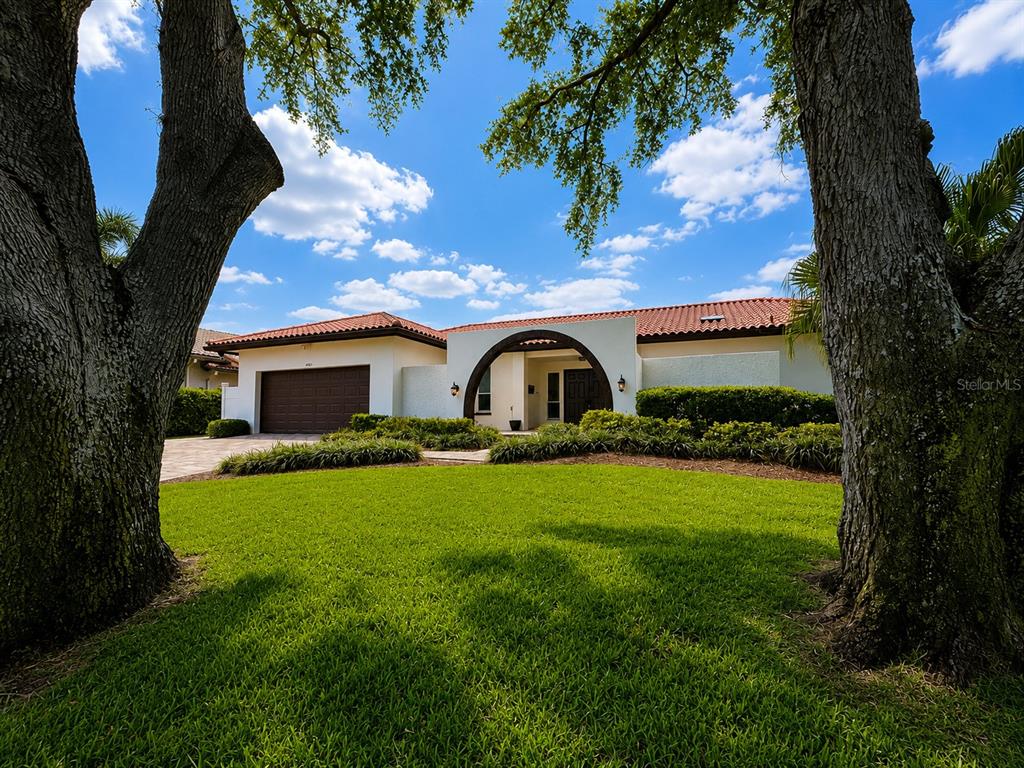 A single-story house with a tile roof, arched entryway, and garage sits behind a grassy lawn — 4901 LANSING ST NE, ST PETERSBURG, FL