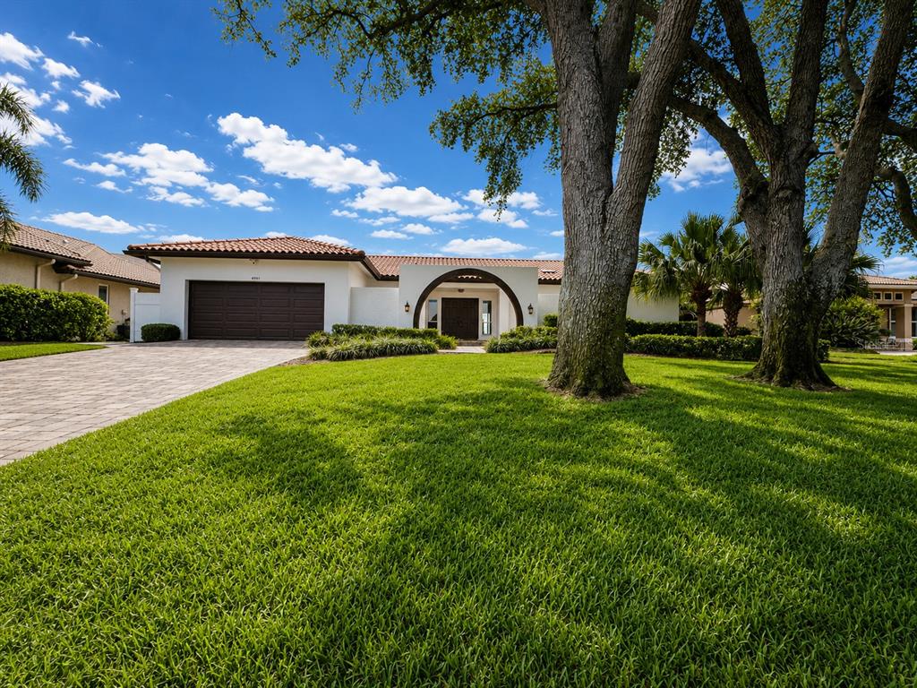 A single-story house with a tile roof, brown garage door, and arched entryway — 4901 LANSING ST NE, ST PETERSBURG, FL