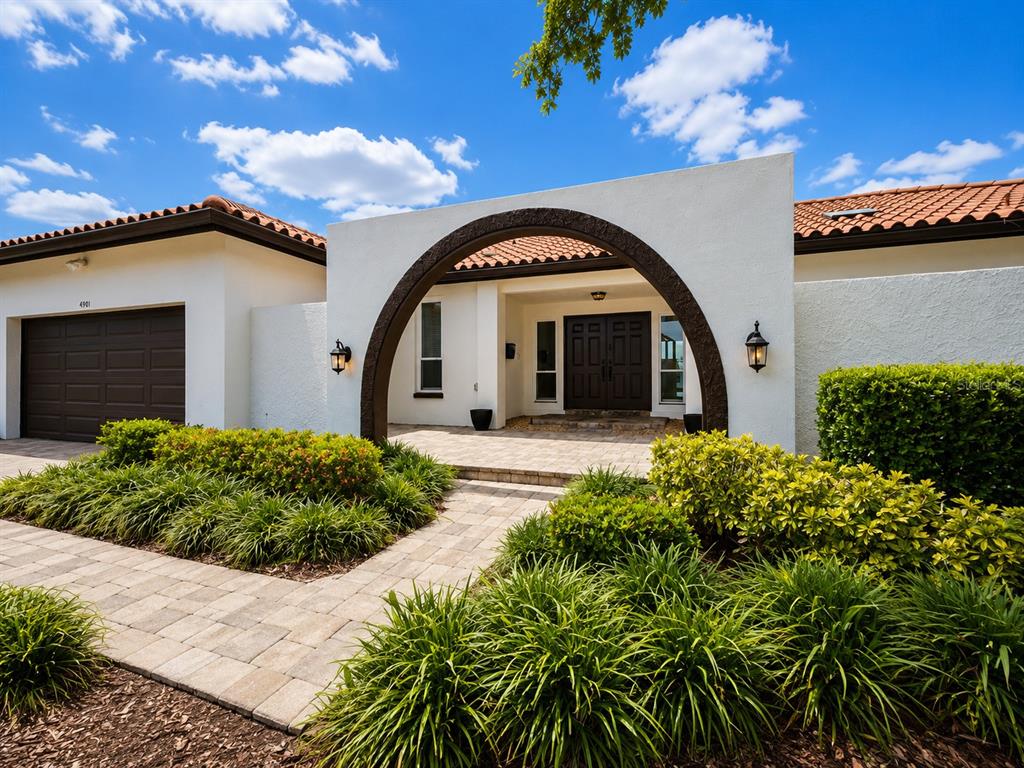 A single-story house with a white stucco facade, a dark arched entryway, and a tiled roof — 4901 LANSING ST NE, ST PETERSBURG, FL