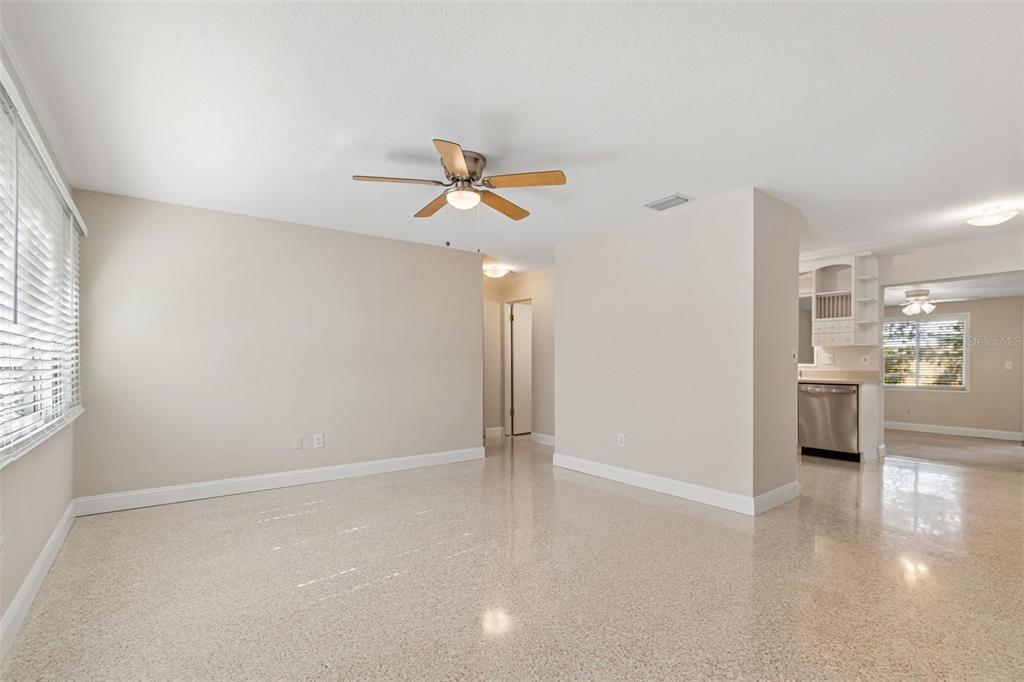 An empty living room with light-colored walls, a ceiling fan, and speckled tile flooring — 200 EVELYN AVE, CLEARWATER, FL