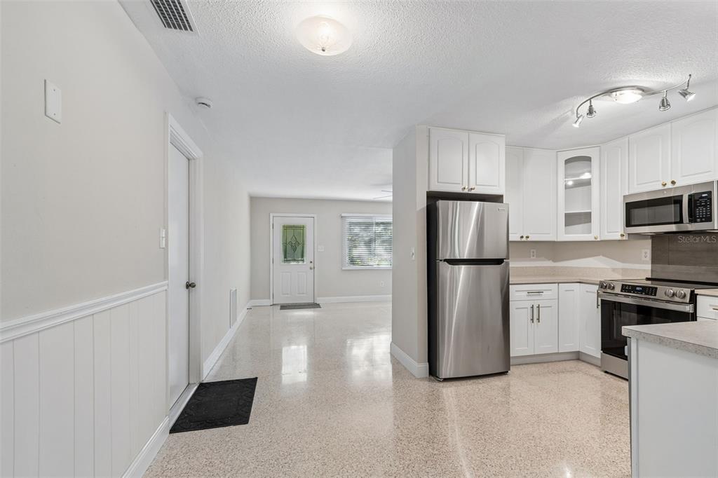 A kitchen with white cabinets and stainless steel appliances opens into a living area — 200 EVELYN AVE, CLEARWATER, FL