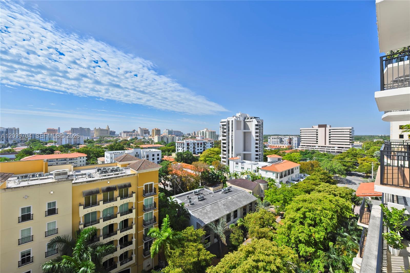 An elevated view shows a cityscape with apartment buildings, lush trees, and a clear sky — 888 S Douglas Rd # 910, Coral Gables FL 33134, CORAL GABLES, FL