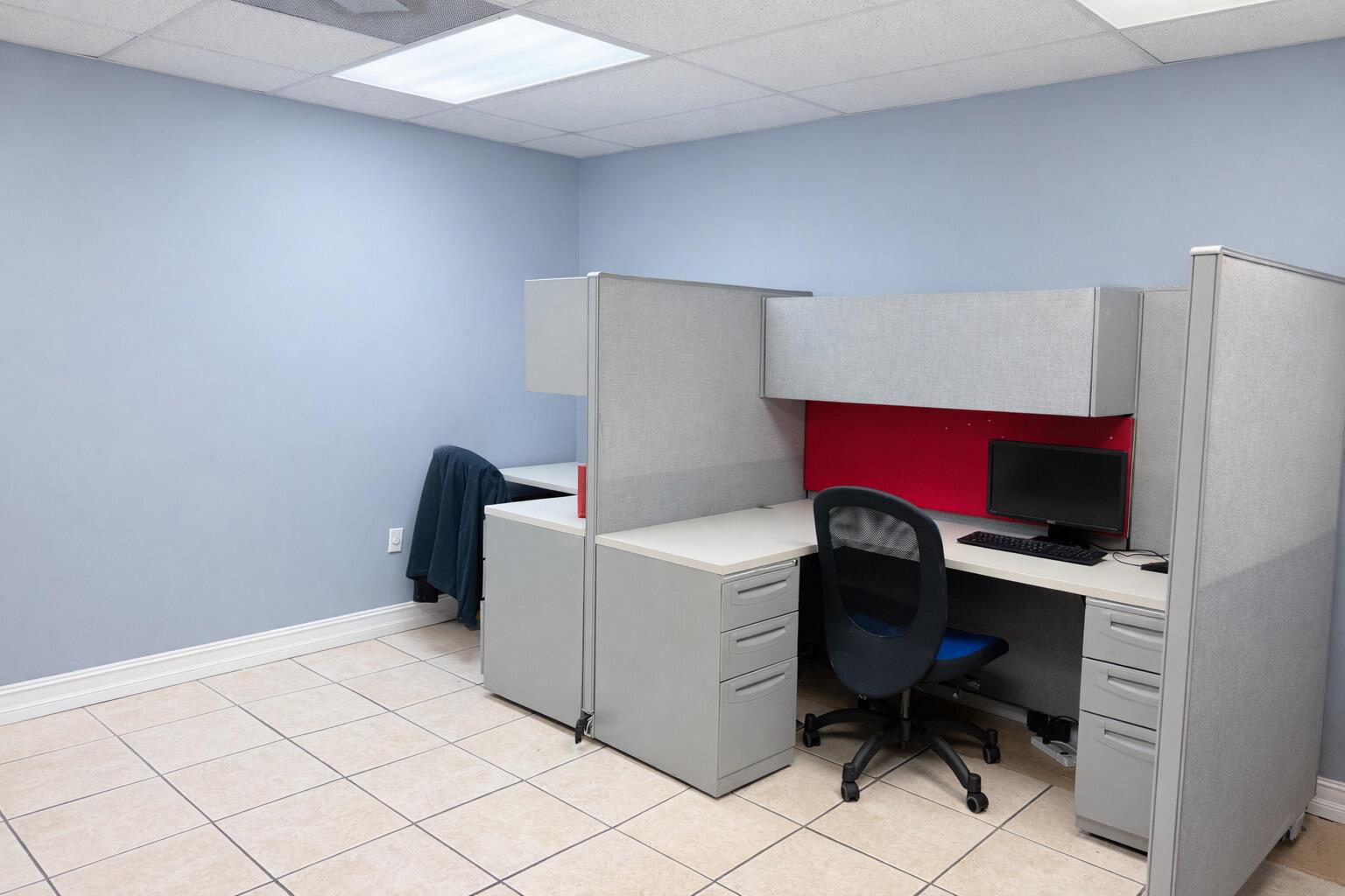 An office cubicle with a desk, chair, and computer sits in a room with tiled floors — 4560 Us Highway 1, Vero Beach FL 32967, VERO BEACH, FL
