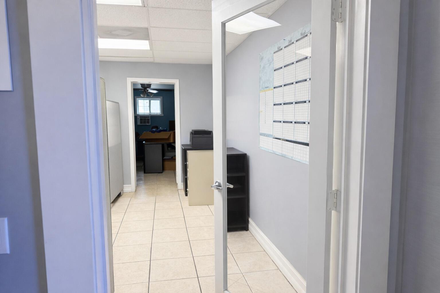 A view through an open glass door into an office with tiled floors and shelving — 4560 Us Highway 1, Vero Beach FL 32967, VERO BEACH, FL