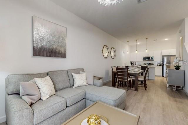 A living room with a gray sectional sofa opens into a kitchen with white cabinets — 209 FAMAGUSTA DRIVE, DAVENPORT, FL