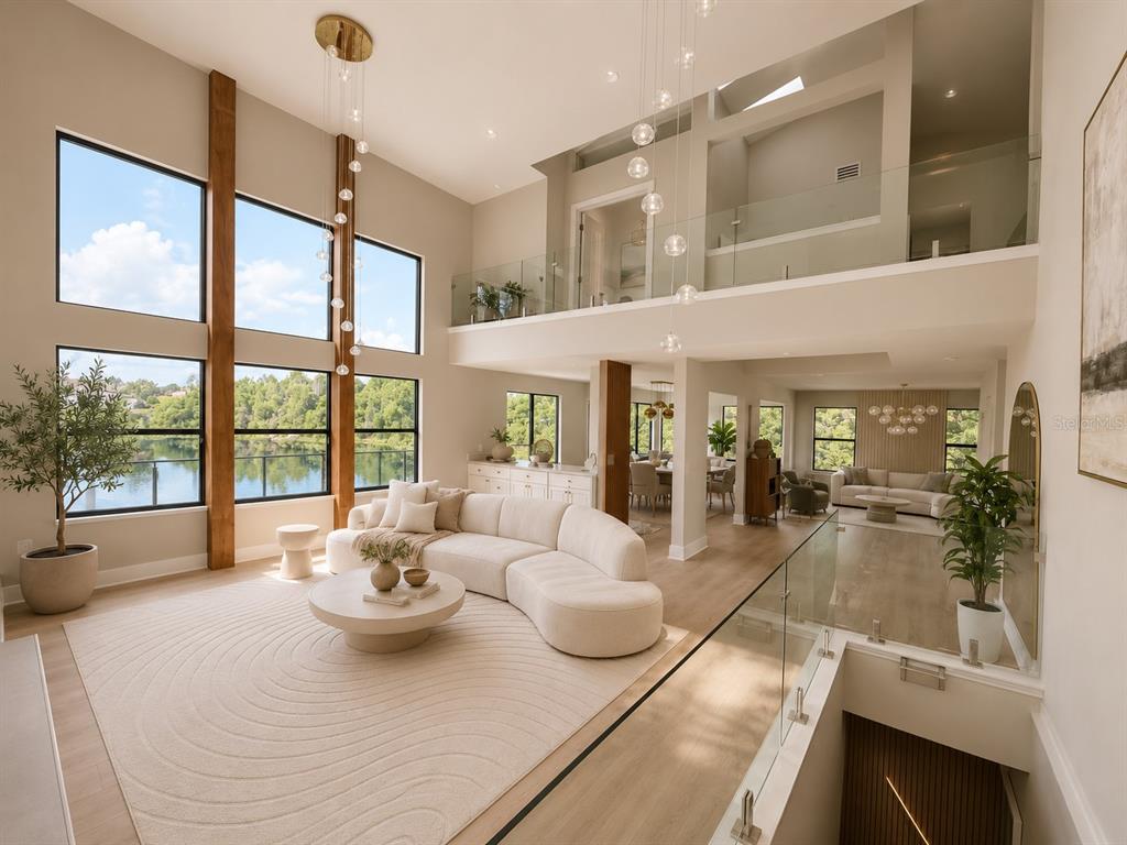 A bright, two-story living room features a curved sofa, large windows, and a glass railing — 7826 PINE HAVEN COURT, ORLANDO, FL