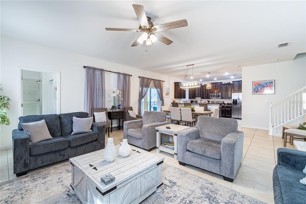 An open-concept living room and kitchen feature gray furniture, a white coffee table, and tile — 9024 SHADOW MOUNTAIN STREET, DAVENPORT, FL