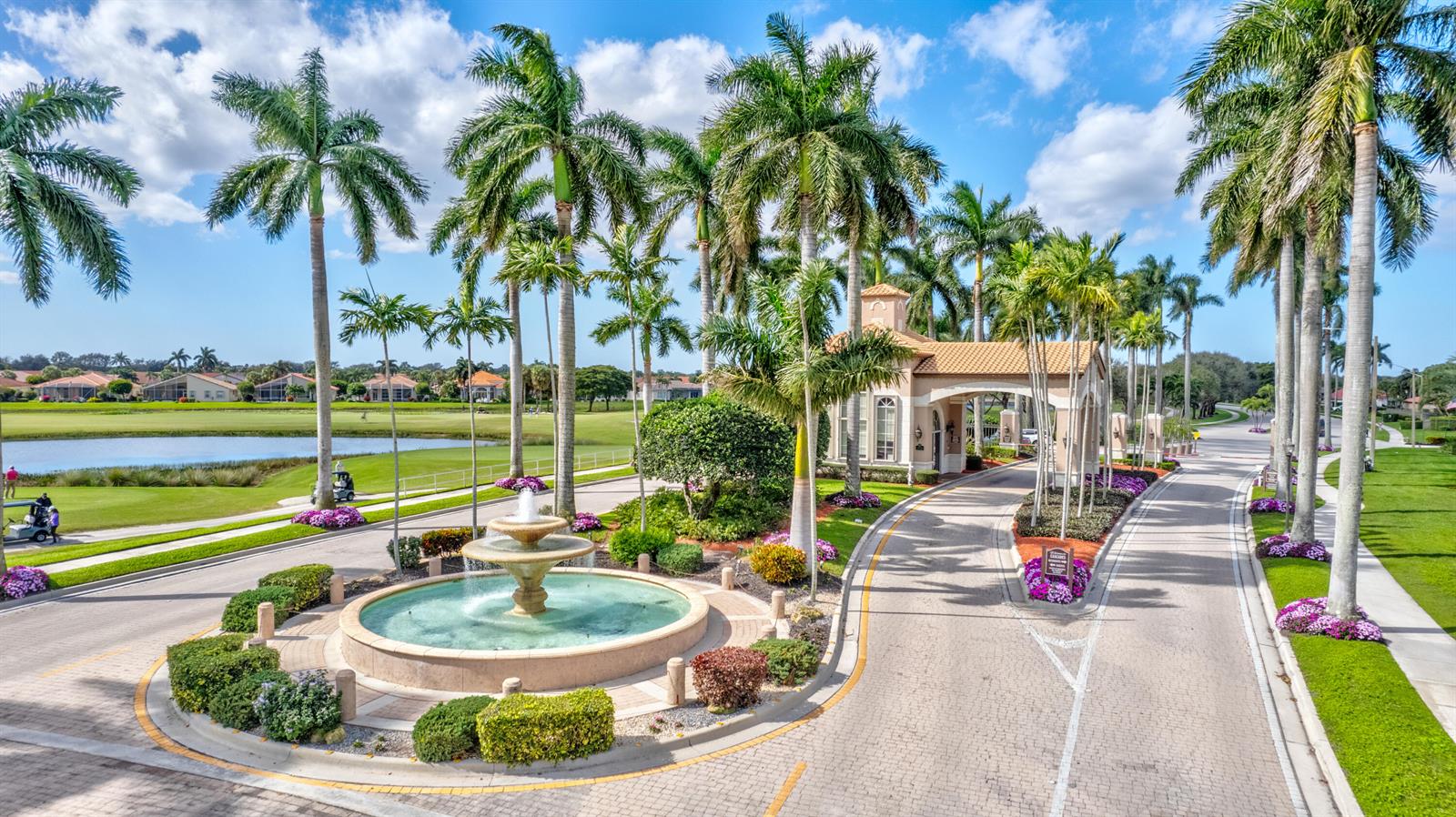 An aerial view of a gated community entrance featuring a fountain and palm trees — 6715 Chimere Terrace, Boynton Beach FL 33437, BOYNTON BEACH, FL