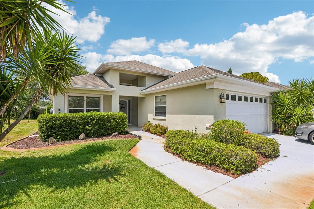 A single-story house with a light-colored exterior, a two-car garage, and a landscaped front yard — 1129 DALESIDE LANE, NEW PORT RICHEY, FL