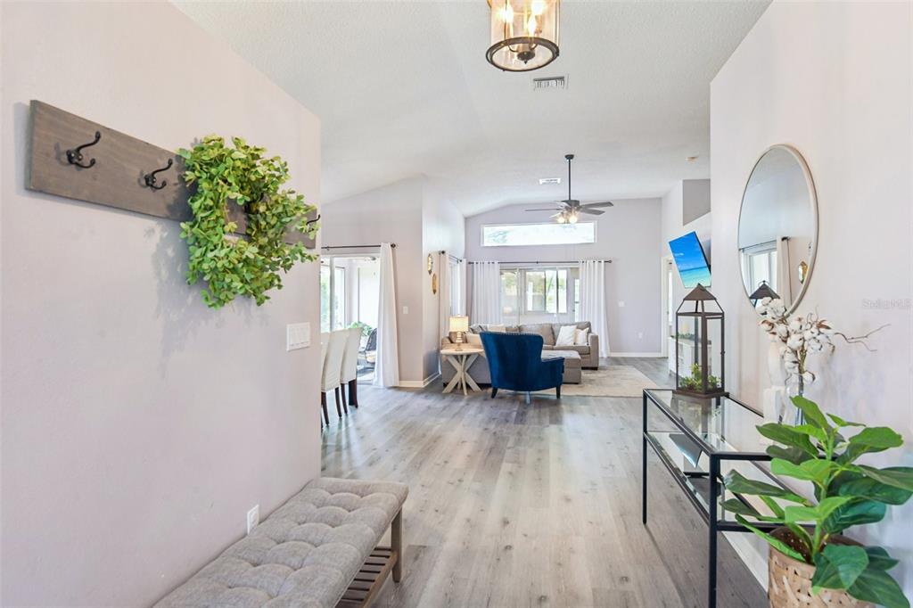 An entryway leads into a living room with light wood floors and vaulted ceilings — 1129 DALESIDE LANE, NEW PORT RICHEY, FL