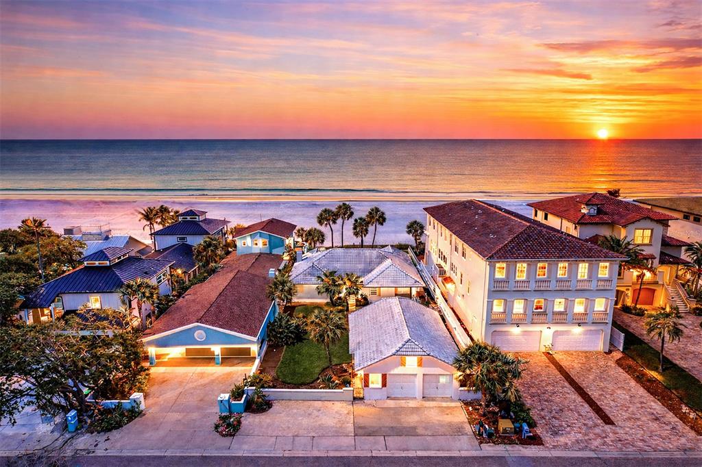 An aerial view of beachfront houses at sunset with a large multi-story home on the right — 18206 SUNSET BOULEVARD, REDINGTON SHORES, FL