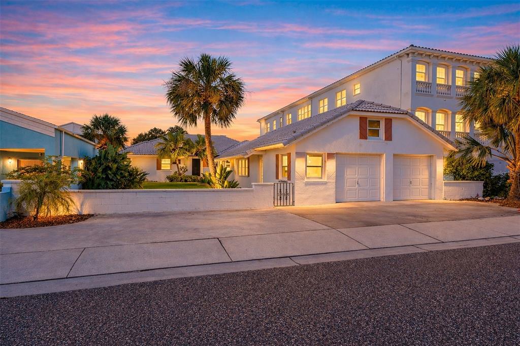 A white house with a two-car garage and palm trees at sunset — 18206 SUNSET BOULEVARD, REDINGTON SHORES, FL