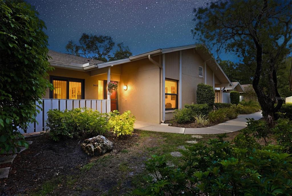 A single-story house with a beige exterior and a lit walkway at night — 3412 TALLYWOOD CIRCLE UNIT 7018, SARASOTA, FL