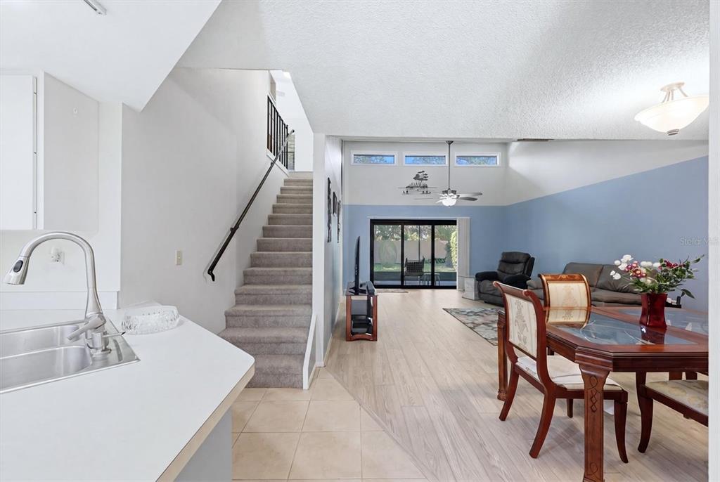 A kitchen overlooks a dining area and living room with stairs and vaulted ceilings — 3412 TALLYWOOD CIRCLE UNIT 7018, SARASOTA, FL