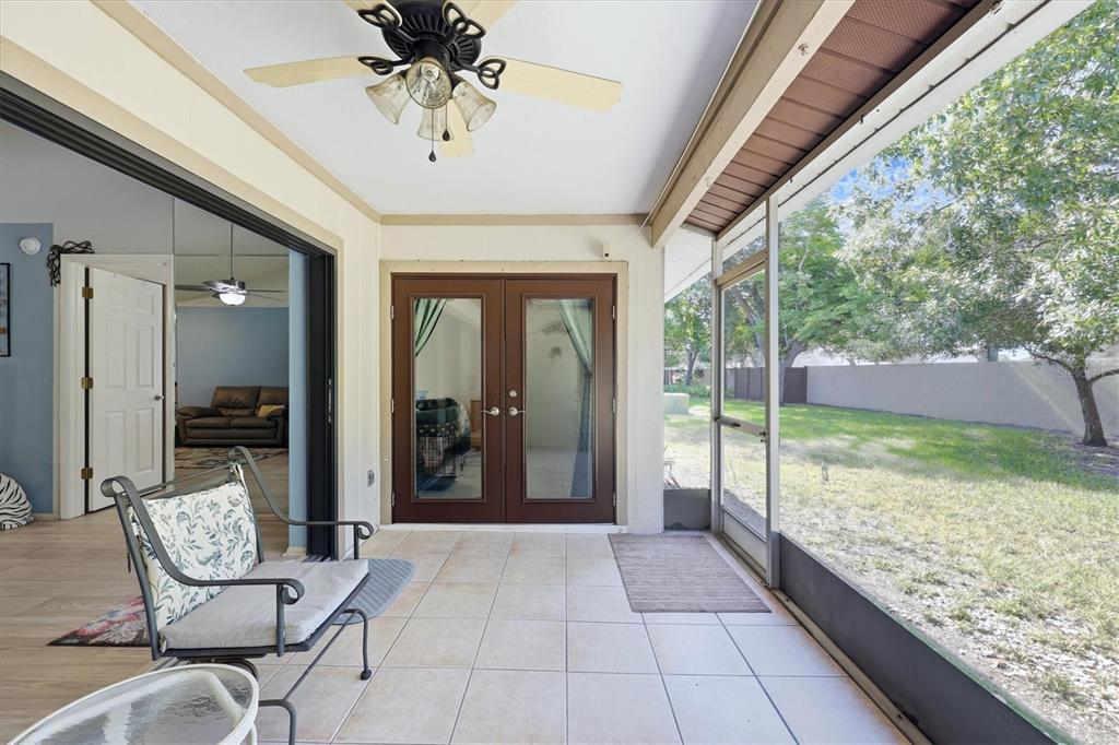 A tiled, screened-in patio features a ceiling fan, double glass doors, and a backyard view — 3412 TALLYWOOD CIRCLE UNIT 7018, SARASOTA, FL