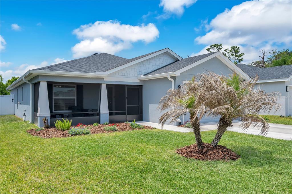 A single-story house with a screened front porch, gray siding, and a palm tree — 2096 GOLDEN BEAK DRIVE, EAGLE LAKE, FL