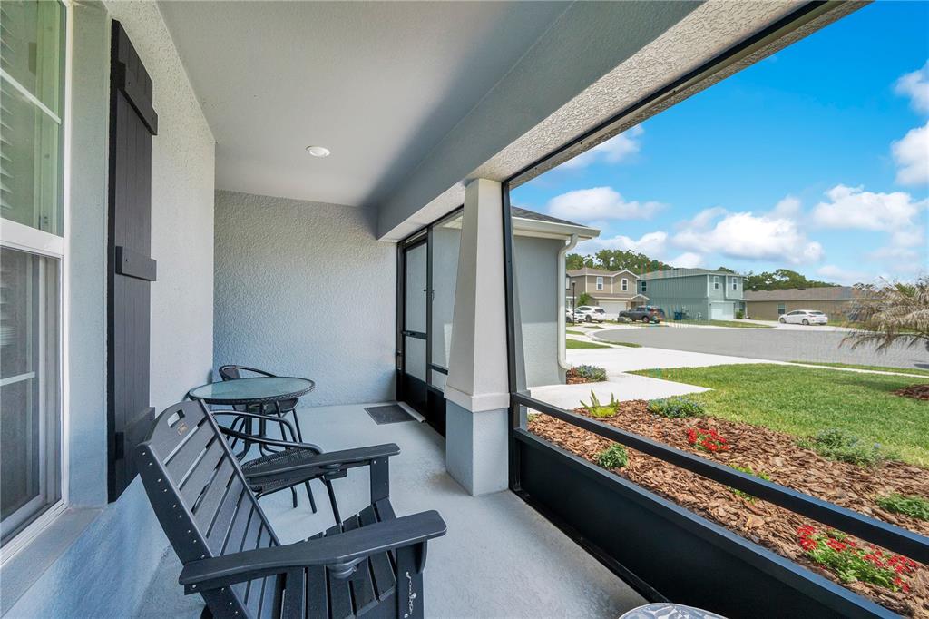 A screened-in porch features a concrete floor, two chairs, a small table, and exterior views — 2096 GOLDEN BEAK DRIVE, EAGLE LAKE, FL