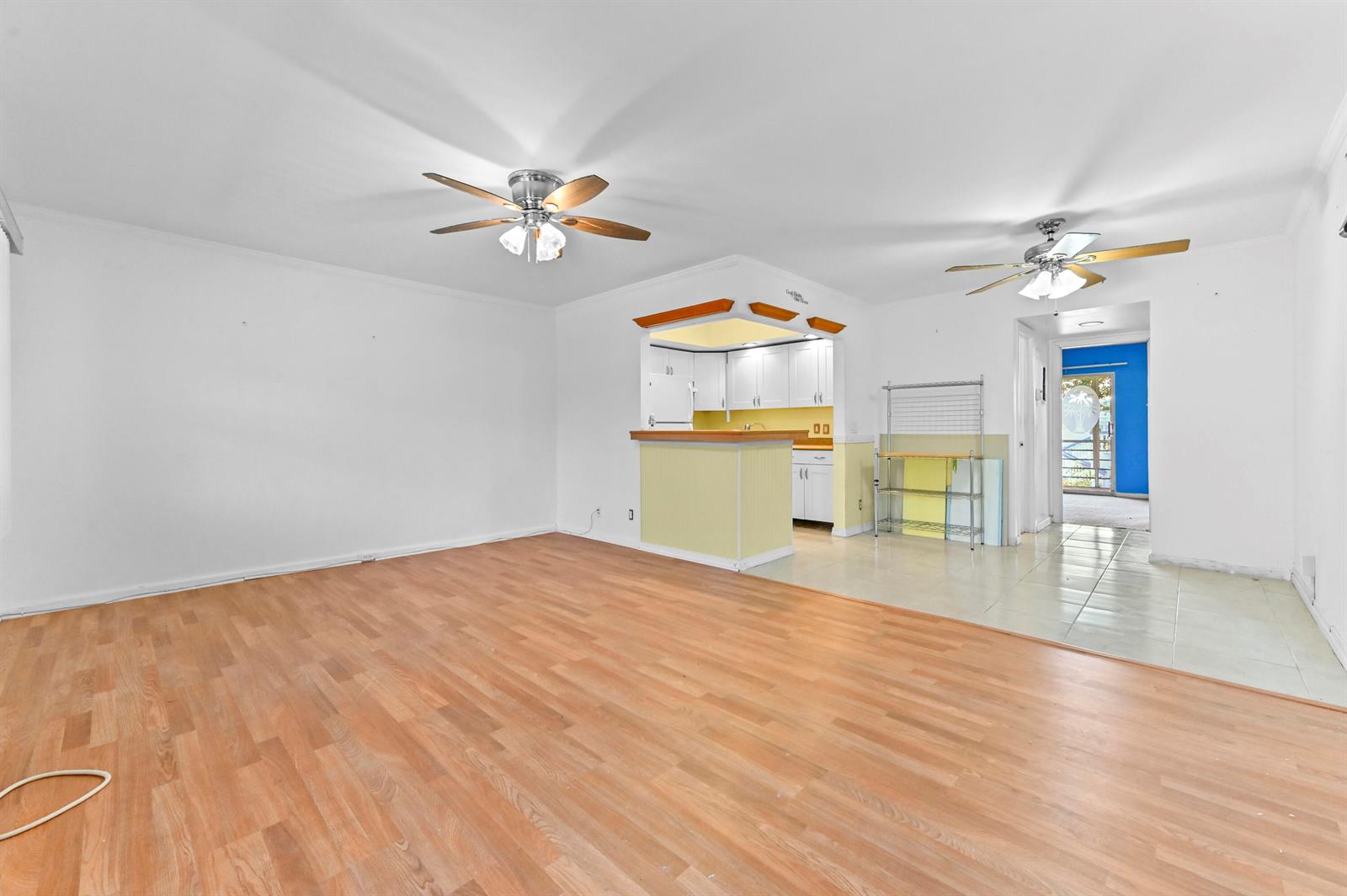 An open-concept living area with wood-look flooring, a kitchen peninsula, and two ceiling fans — 259 Newport P, Deerfield Beach FL 33442, DEERFIELD BEACH, FL