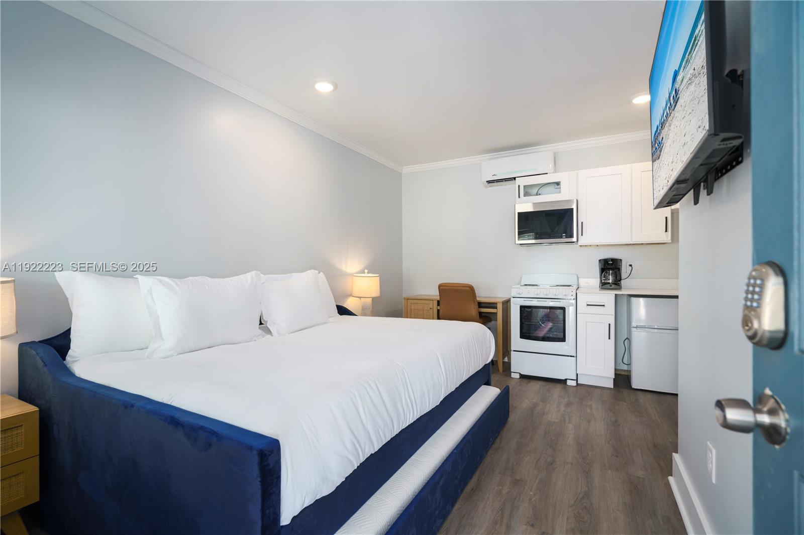 A studio apartment features a blue bed, a small kitchen area, and a desk — 17784 Front Beach Rd # 10, Panama City FL 32413, PANAMA CITY, FL