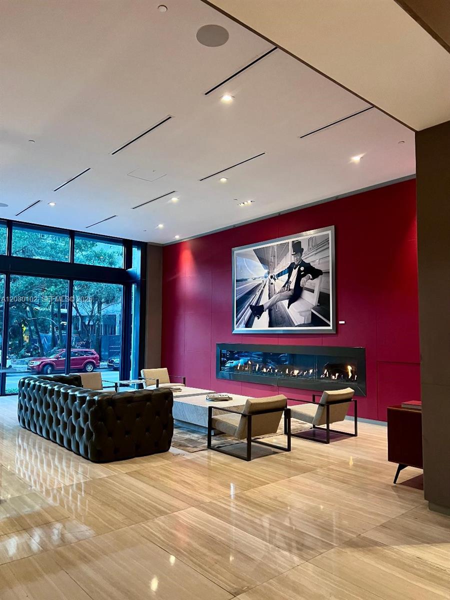A modern lobby features a tufted sofa, armchairs, a fireplace, and a large framed photograph — 1080 Brickell Ave # 3600, Miami FL 33131, MIAMI, FL